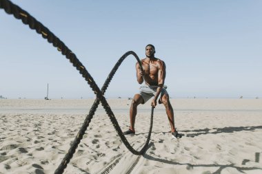 Fit man working out with battle ropes clipart