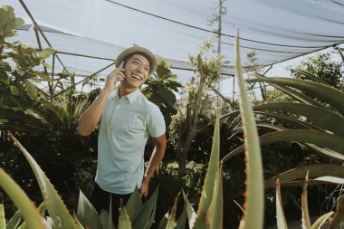 Bir botanik bahçesinde telefonda konuşan neşeli adam