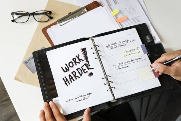 Phrase Work harder written in a notebook by man 