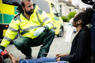 Oksijen maskesi bir yolda yaralı bir kadın için koyarak erkek sağlık görevlisi