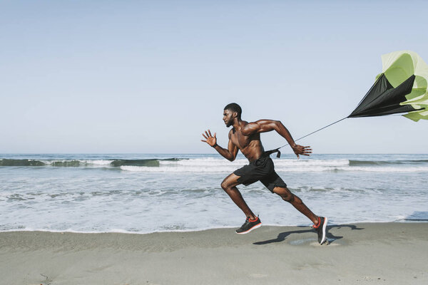 Здоровяк с парашютом на пляже
