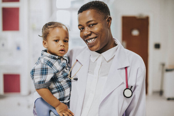 Happy pediatrician carrying a young boy