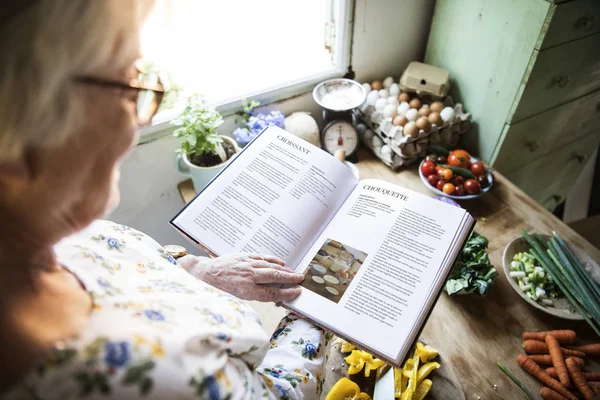 Счастливая Пожилая Женщина Читает Поваренную Книгу — стоковое фото