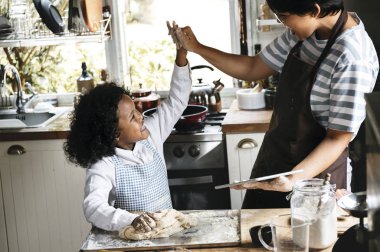 Genç çocuk annesi ile pişirmeye yaslanmış
