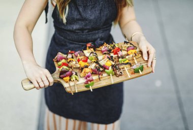 Vegan mangal şiş bir ahşap tahta üzerinde hizmet veren kadın