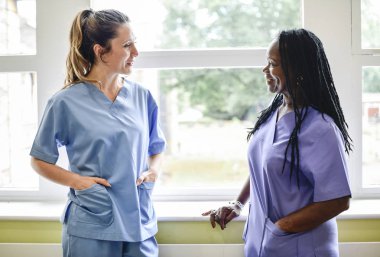 Nurses having a conversation in the hospital hallway clipart