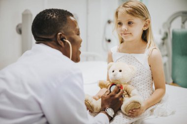 Doctor doing a health checkup on a teddy bear clipart