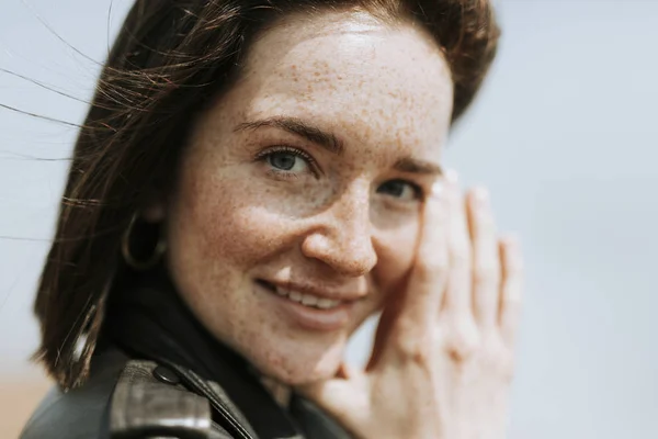 Side view of  a woman in leather jacket standing in a park