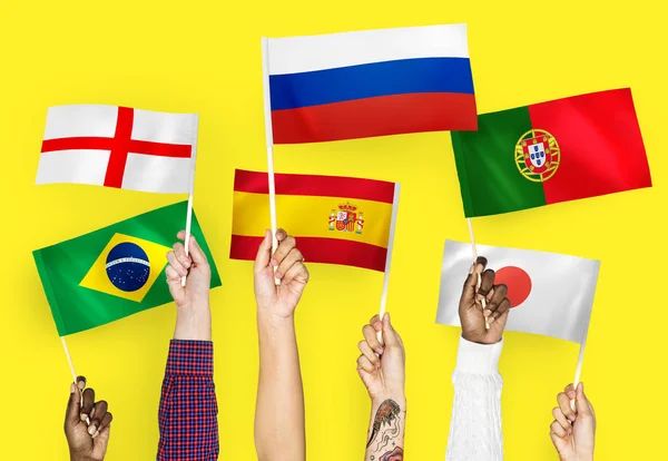 Mãos Levantando Bandeiras Nacionais Inglaterra Espanha Japão Portugal Rússia Brasil — Fotografia de Stock