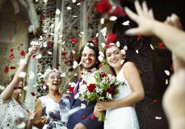Family throwing rose petals at the newly wed bride and groom clipart