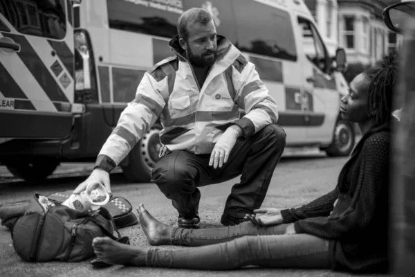 Αρσενικό Παραϊατρικό Τον Έλεγχο Μια Τραυματισμένη Γυναίκα Ένα Δρόμο — Φωτογραφία Αρχείου