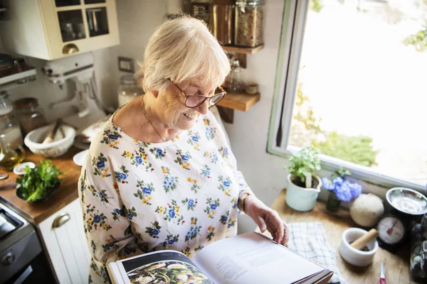 Feliz Anciana Leyendo Libro Cocina —  Fotos de Stock