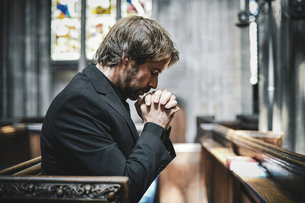 Lonely Christian man praying in the church