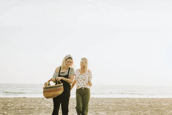 朋友们拿着野餐篮在海滩上散步 — 图库照片
