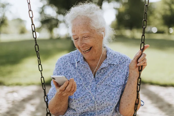 Fröhliche Seniorin Hört Musik Auf Spielplatz — Stockfoto