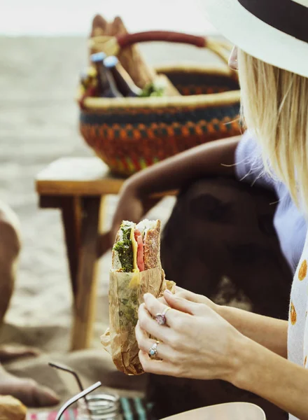 ビーチ ピクニックでサンドイッチを食べる女 — ストック写真