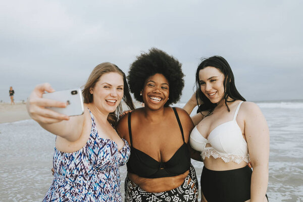 Beautiful curvy women taking a selfie at the beach