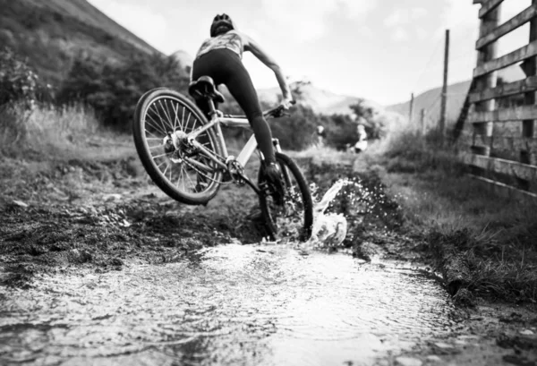 Γυναίκα Ποδηλάτης Στη Δράση Κατά Διάρκεια Μια Λακκούβα — Φωτογραφία Αρχείου