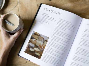 Bir yemek kitabı okuma ve bir çay bardağı tutan kadın