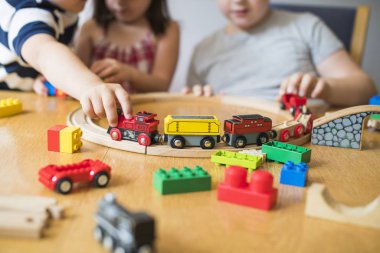 Bloklar, trenler ve otomobiller ile oynayan kardeşler