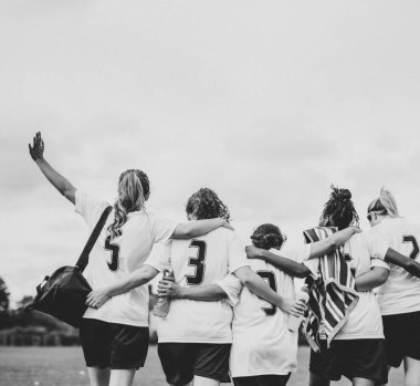 Female football players huddling and walking together clipart