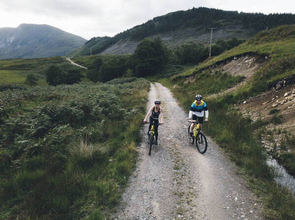 Couple cycling down a road in the Scottish Highlands