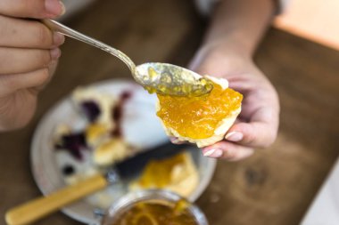 Kaşığı çörek parçası üzerinde narenciye reçeli