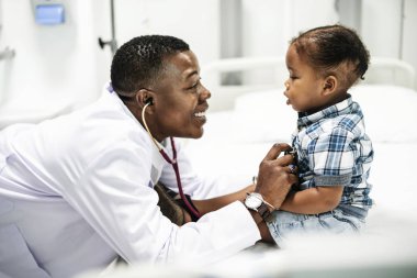 Cheerful pediatrician doing a medical checkup of a young boy clipart