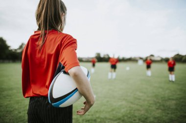 Onun kollarında topu tutan kadın rugby oyuncusu