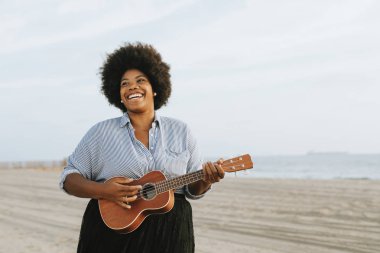 Afro-Amerikan müzisyen ukulele kumsalda oynarken