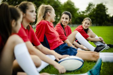 Çimenlerin üzerinde oturan mutlu kadın rugby oyuncuları