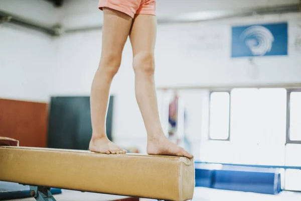 Young gymnast balancing on a balance beam