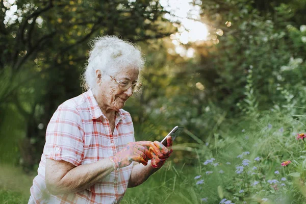 Ανώτερος Γυναίκα Χρησιμοποιώντας Τηλέφωνο Ενώ Κηπουρική — Φωτογραφία Αρχείου