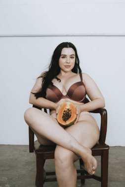 Bir papaya ile kısmen çıplak kadın