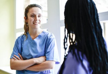 Nurses having a conversation in the hospital hallway clipart