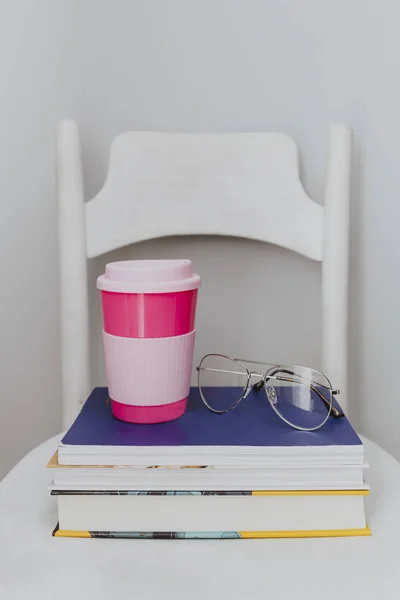 一叠教科书上的粉红旅行杯 — 图库照片