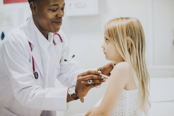 Pediatrician measuring the temperature of a young girl