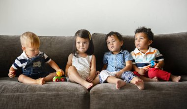Diverse young kids sitting on the couch together clipart