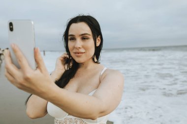 Plajda bir selfie alarak neşeli artı boyutu kadın