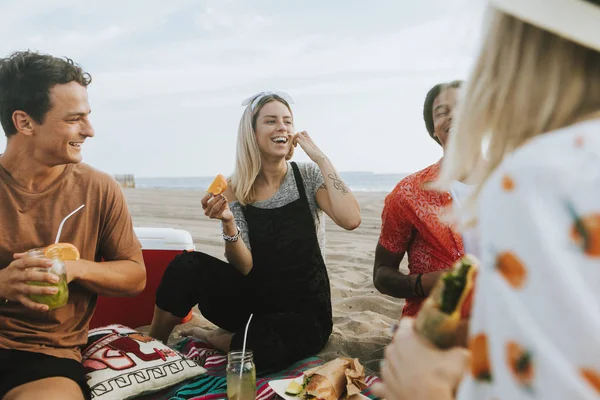 ビーチ ピクニックで食べ物を食べている友人 — ストック写真