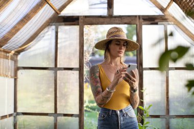 Bahçıvan serada telefonunu kullanarak