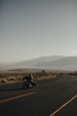 Adam ABD manzaralı bir yoldan bir motosiklet sürme