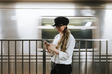 Metro platformunda tren beklerken müzik dinleyen kız