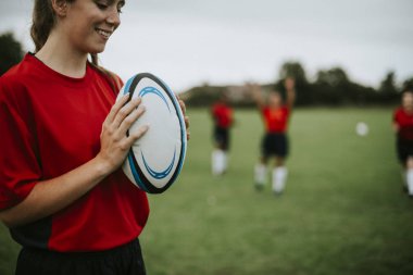 Mutlu kadın rugby oyuncusu bir top tutan