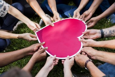 Pembe kalp simgesi tutan insanlar grubu
