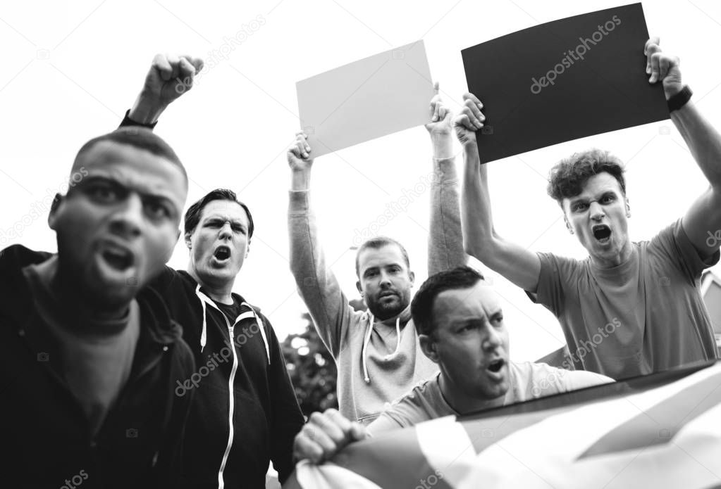 Group of angry men showing a UK flag and blank boards shouting during a protest