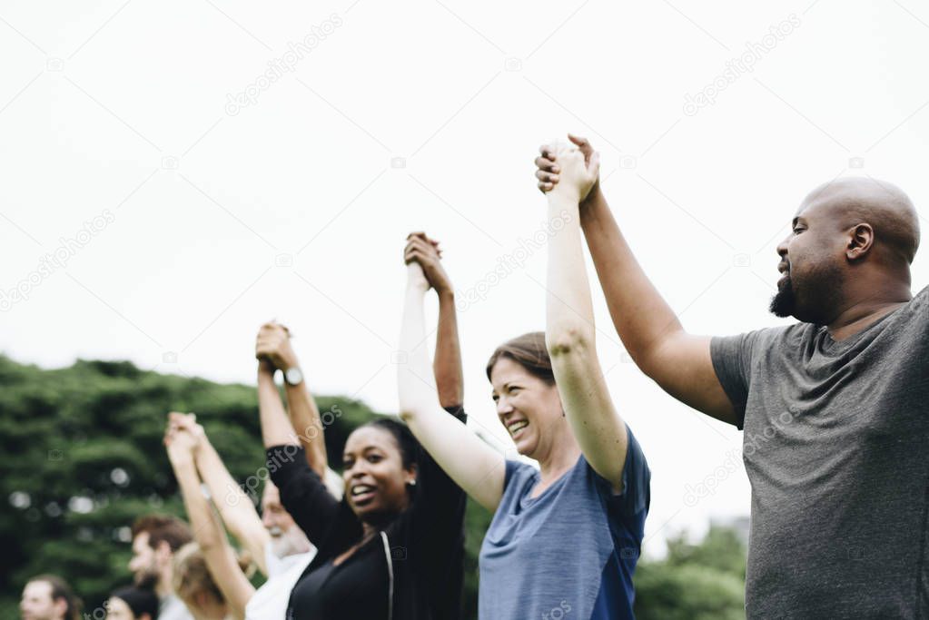 Happy diverse people holding hands in the park