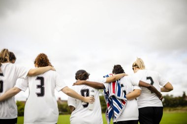 Female football players huddling and walking together clipart