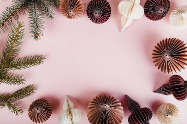 Kağıt topu çelenk ve çam dalları pembe bir arka plan üzerinde