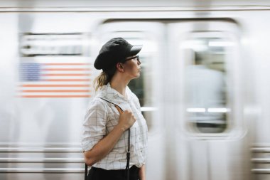 Metro platformunda tren bekleyen düşünceli kadın